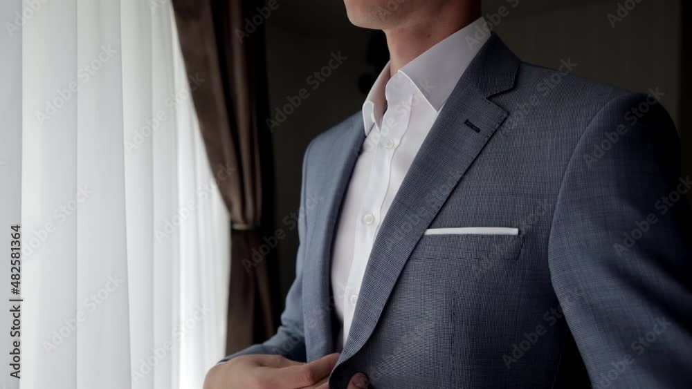 Close up view of man adjusts his suit. Business man put suit on during morning routine at home, preparing to go to work