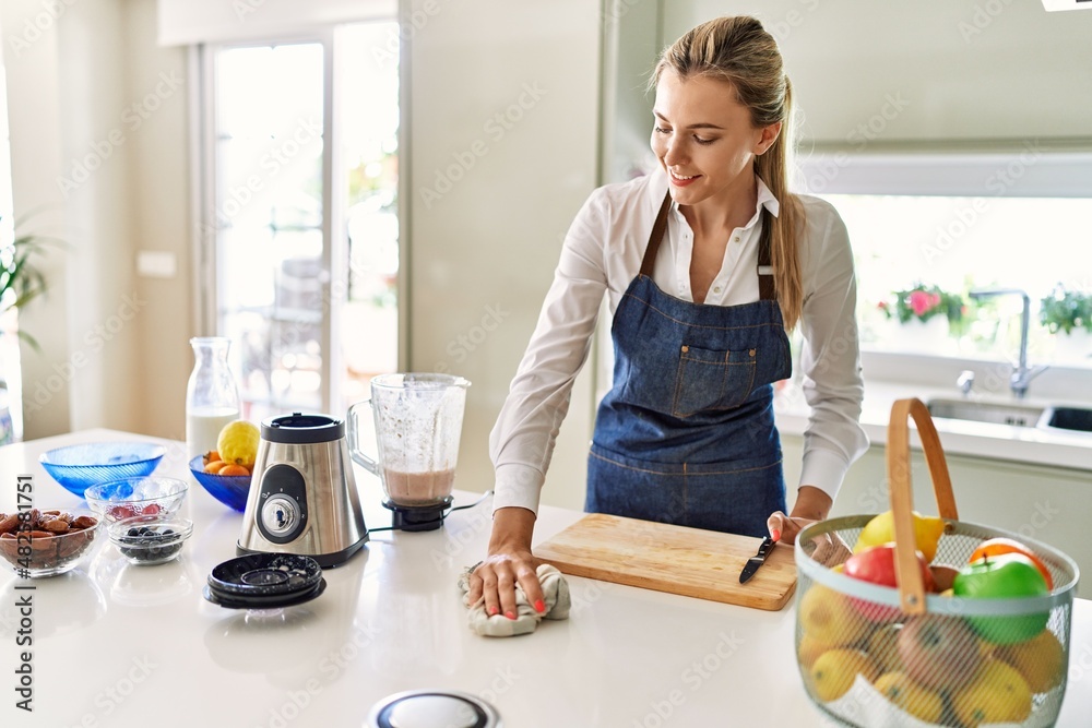 Young blonde woman smiling confident cleaning table at kitchen Young blonde woman smiling confident cleaning table at kitchen