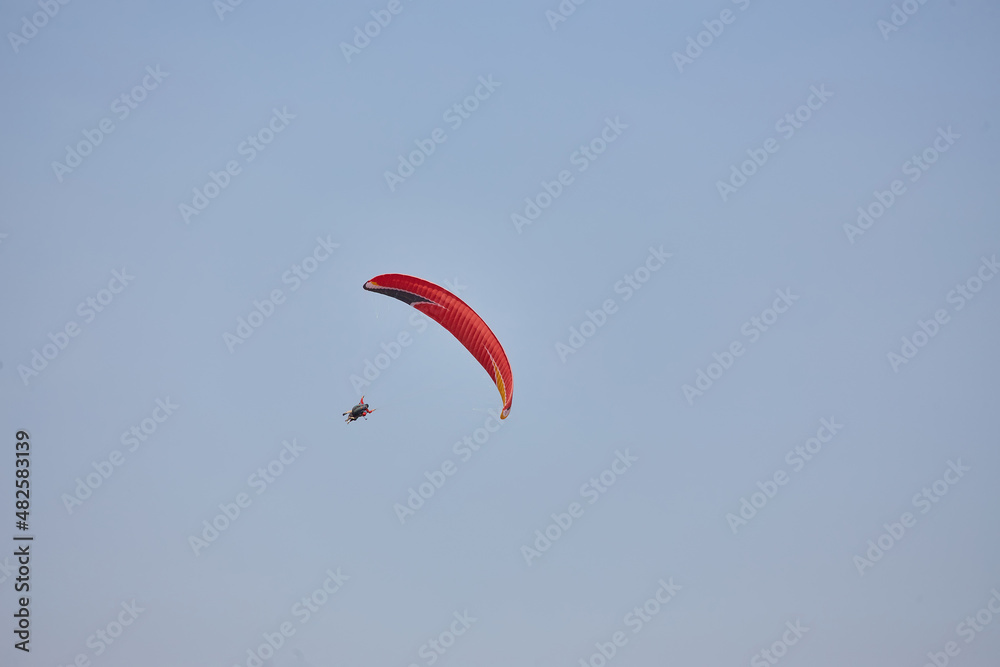 Paragliding in the sky. Paraglider flying in bright sunny day. Beautiful paraglider in flight on a turquise background. Paragliding in the sky. Paraglider flying in bright sunny day. Beautiful paraglider in flight on a turquise background.