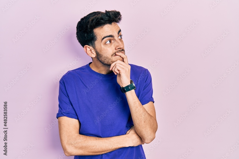 Young hispanic man wearing casual t shirt thinking worried about a question, concerned and nervous with hand on chin Young hispanic man wearing casual t shirt thinking worried about a question, concerned and nervous with hand on chin