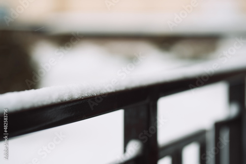 photograph of a stair railing covered in snow with a blurred background