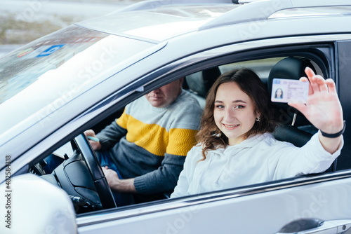 Fototapeta Happy young caucasian woman driving her new car holding car license