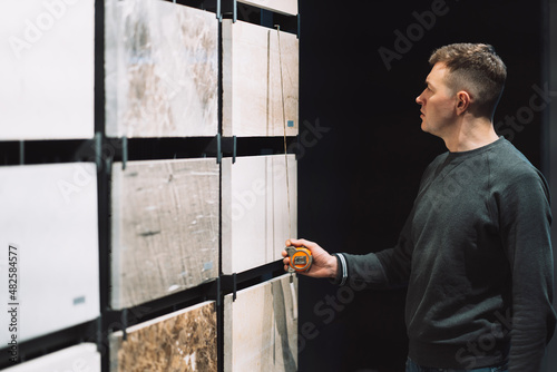 a man stands in a shop near a stand with samples of beautiful granite and marble