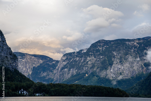 Hallstatt, Austria, 27 August 2021: Alps Mountain Krippenbrunn near alpine deep blue lake at summer day, coniferous forest on hillside, clouds and evening sky, Schloss Grub, Salzkammergut