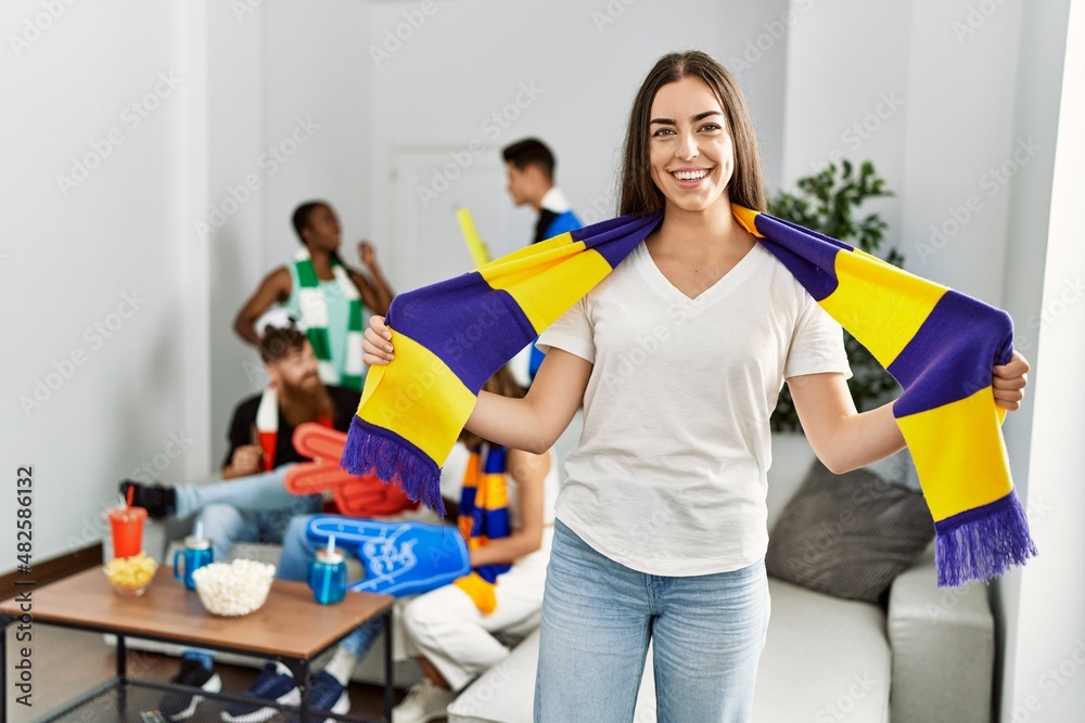 Young soccer hooligan woman smiling happy holding team scarf at home Young soccer hooligan woman smiling happy holding team scarf at home