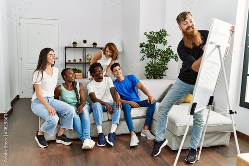 Quadro su tela Group of young friends smiling happy playing drawing game at home