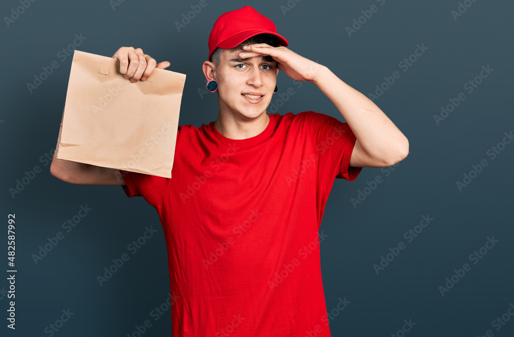 Young caucasian boy with ears dilation holding take away paper bag stressed and frustrated with hand on head, surprised and angry face Young caucasian boy with ears dilation holding take away paper bag stressed and frustrated with hand on head, surprised and angry face