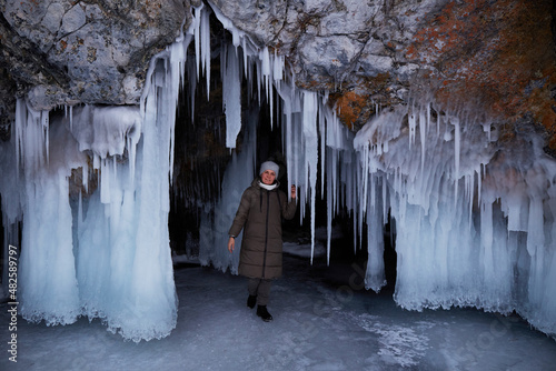 Winter trip on the frozen Lake Baikal. A woman in a cave covered huge icicles. 