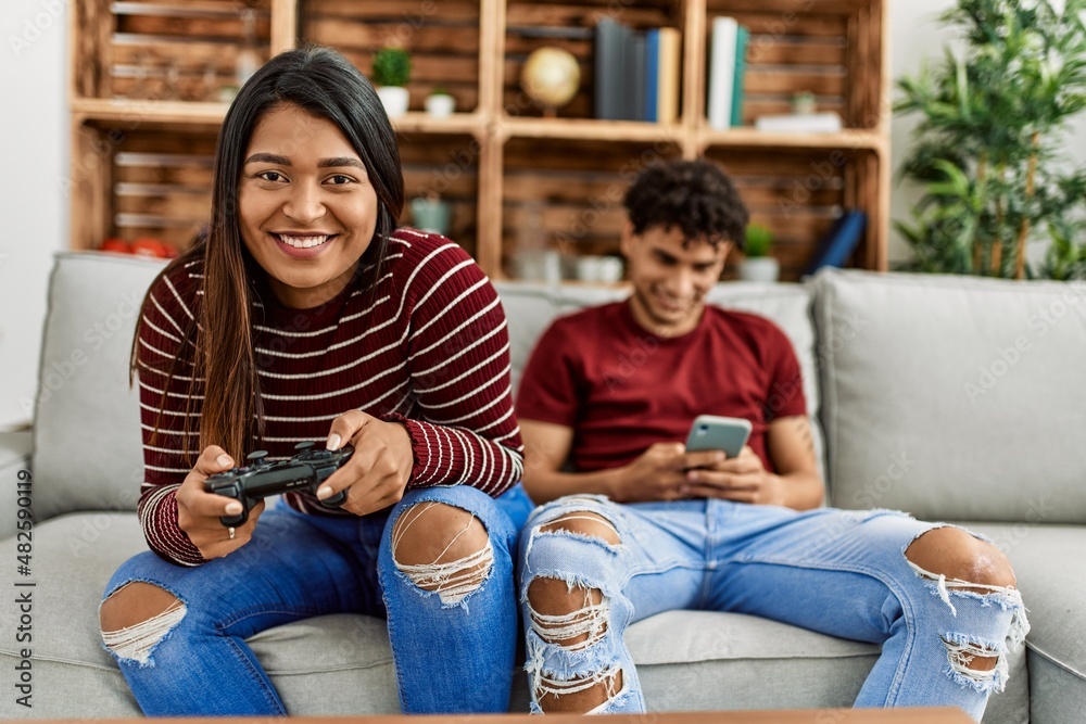 Woman playing video game and man using smartphone at home. Woman playing video game and man using smartphone at home.