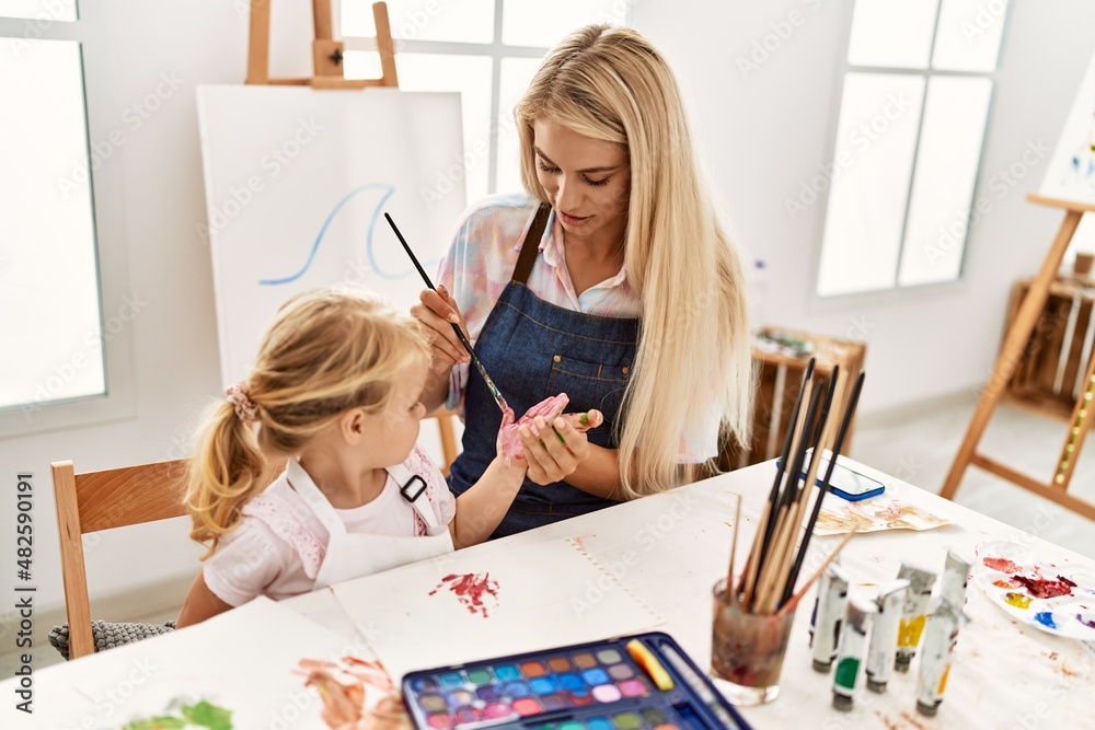 Fototapeta premium Mother and daughter smiling confident painting palm hands at art studio