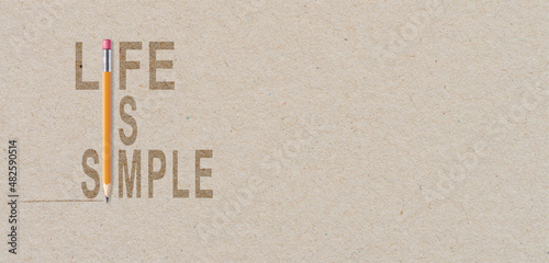 Life is simple - motivational quote on brown paper with orange pencil