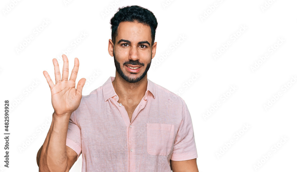 Naklejka premium Hispanic man with beard wearing casual shirt showing and pointing up with fingers number five while smiling confident and happy.