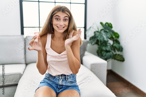 Young blonde woman holding menstrual cup celebrating victory with happy smile and winner expression with raised hands photo