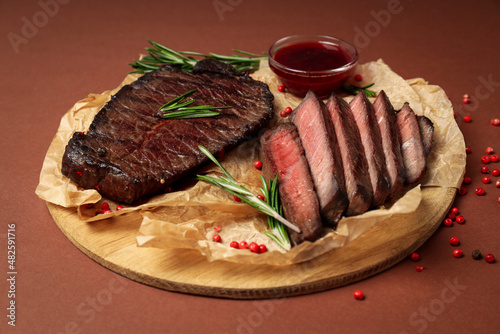 Concept of tasty food with beef steaks on brown background