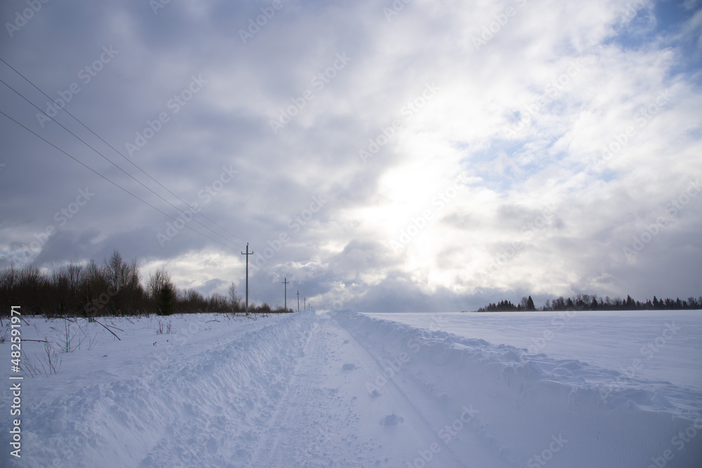 A deserted country road through snow-covered fields. Poor visibility due to a snowstorm.