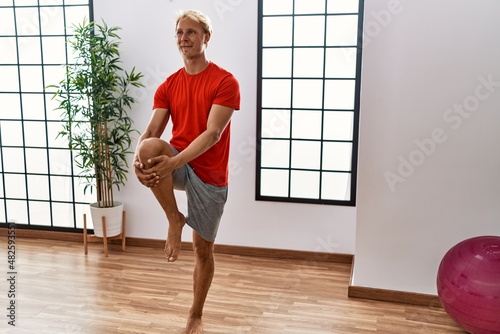 Young caucasian man smiling confident stretching at sport center