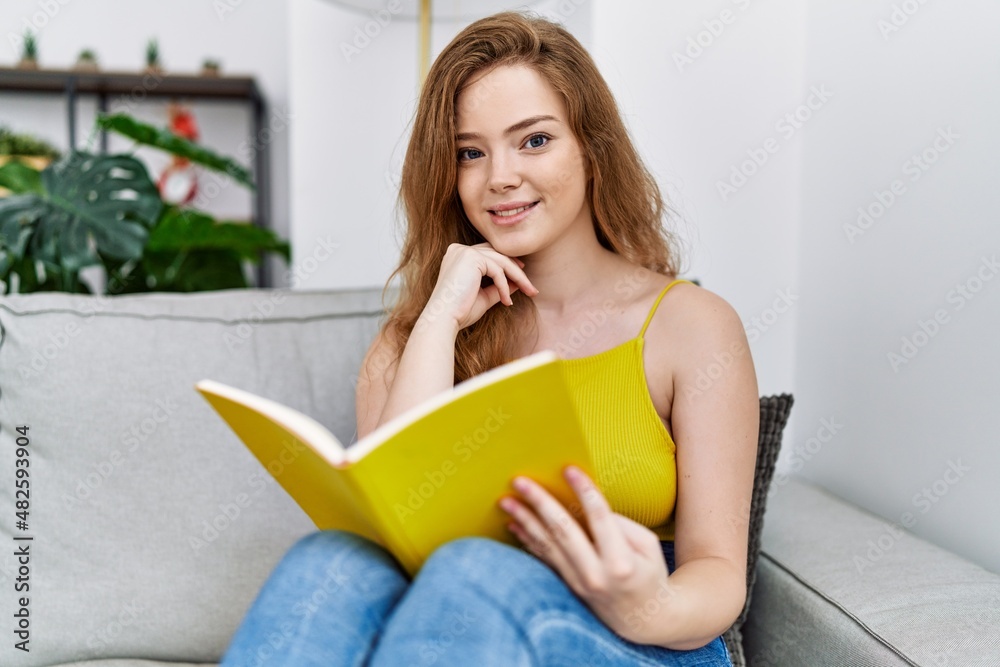 Young redhead girl smiling happy reading book at home Young redhead girl smiling happy reading book at home