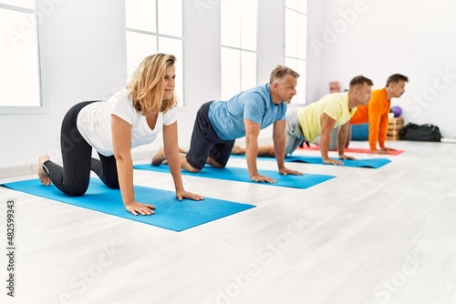Group of middle age people concentrate training yoga at sport center.