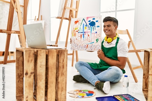 Young hispanic man smiling confident having online draw class at art studio
