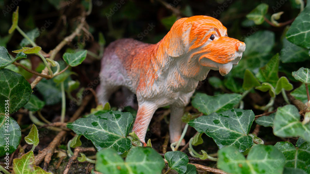 Obraz premium Toy dog figurine surrounded by green leaves.