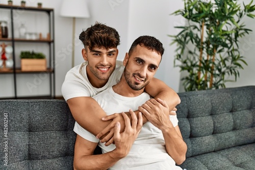 Two hispanic men couple smiling confident and hugging each other at home