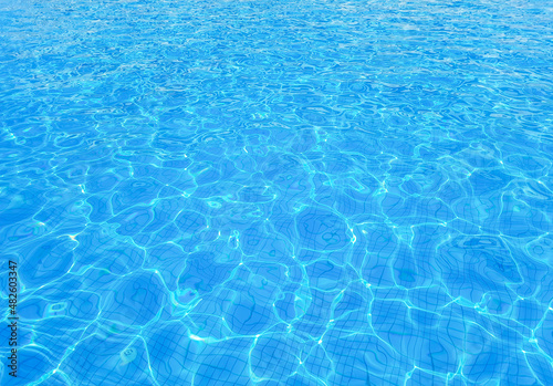 Beautiful bright sunny surface of swimming pool water with rippling wavy glowing blue transparent water. Abstract water surface with rippling waves background