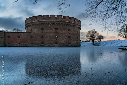 Old brick tower surrounded by a frozen moat