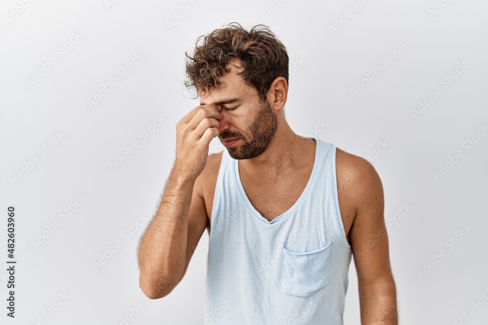 Young handsome man standing over isolated background tired rubbing nose and eyes feeling fatigue and headache. stress and frustration concept. Young handsome man standing over isolated background tired rubbing nose and eyes feeling fatigue and headache. stress and frustration concept.