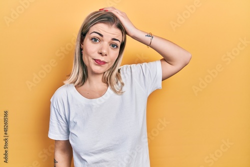Beautiful caucasian woman wearing casual white t shirt confuse and wonder about question. uncertain with doubt, thinking with hand on head. pensive concept.