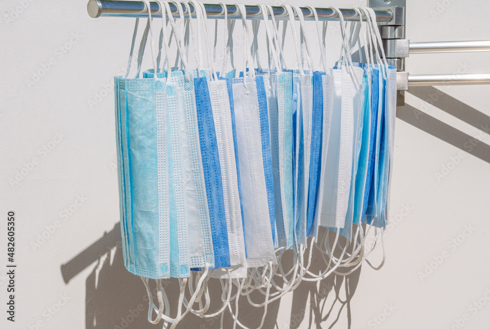 Many blue and white medical protective face masks hanging outdoor under bright hot sunlight Many blue and white medical protective face masks hanging outdoor under bright hot sunlight
