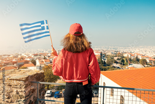 Happy student girl with a Greek flag at city viewpoint. The concept of citizenship and learning Greek language in university