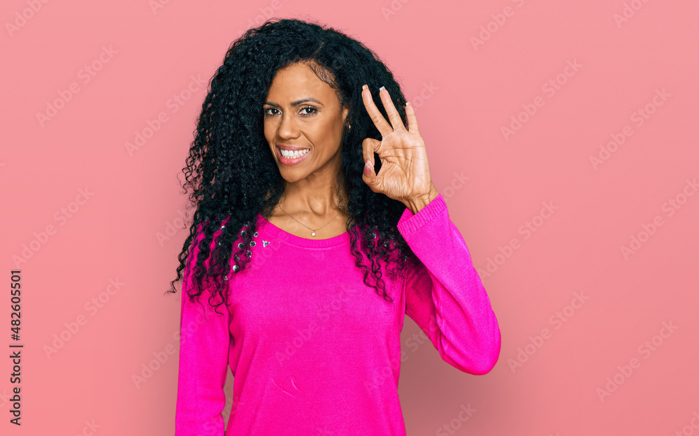 Middle age african american woman wearing casual clothes smiling positive doing ok sign with hand and fingers. successful expression. Middle age african american woman wearing casual clothes smiling positive doing ok sign with hand and fingers. successful expression.