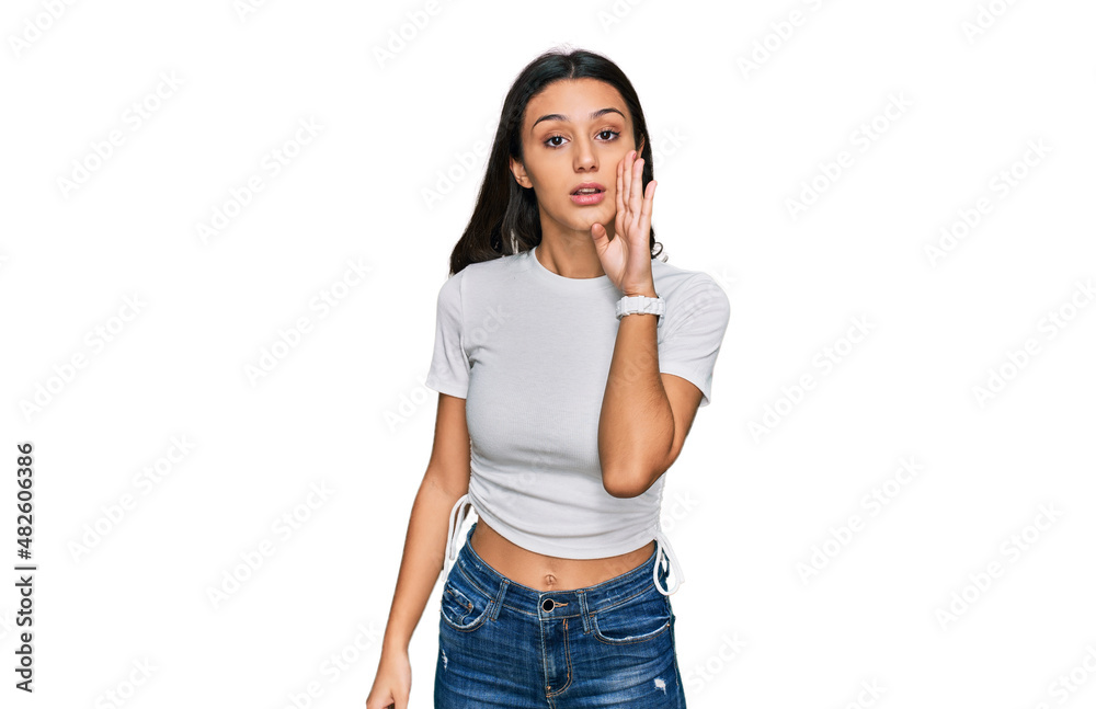 Young hispanic girl wearing casual white t shirt hand on mouth telling secret rumor, whispering malicious talk conversation Young hispanic girl wearing casual white t shirt hand on mouth telling secret rumor, whispering malicious talk conversation