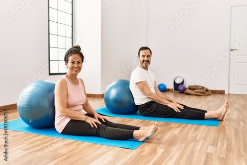 Mature hispanic couple doing excersice and stretching at yoga room. Two adult people doing pilates and flexibility workout photo