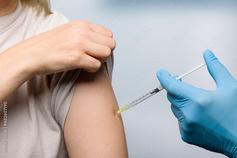 Close up of doctor's hand applying a vaccination in a female arm Close up of doctor's hand applying a vaccination in a female arm