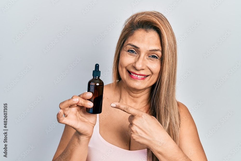 Middle age hispanic woman using night serum smiling happy pointing with hand and finger Middle age hispanic woman using night serum smiling happy pointing with hand and finger