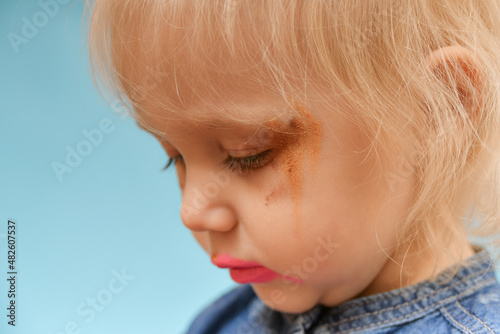 A portrait of a child who put on parental makeup on his own. Small children and high fashion.