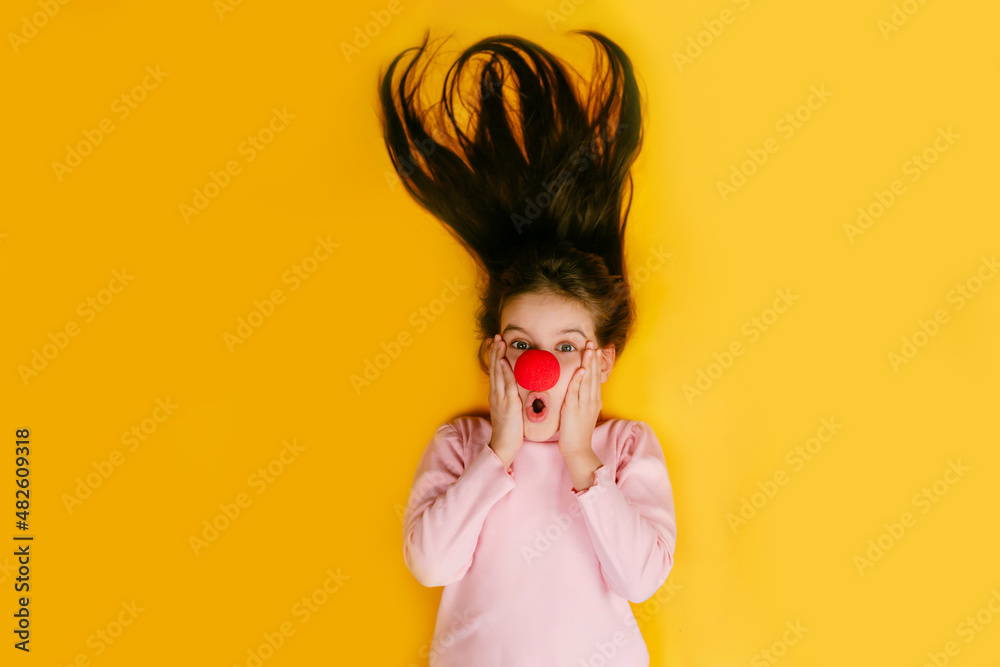 Childy girl with a clown's nose is surprised with her hair up. April 1st. Childy girl with a clown's nose is surprised with her hair up. April 1st.