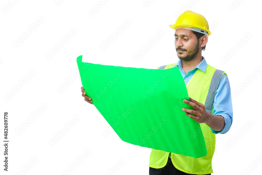 Young Indian engineer wearing yellow color hard hat and cheaking paper on white background. Young Indian engineer wearing yellow color hard hat and cheaking paper on white background.