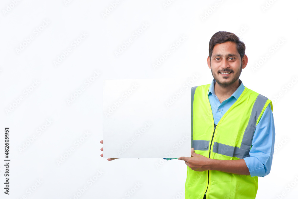 Young indian Construction Worker Showing Empty Poster Board on White Background. Young indian Construction Worker Showing Empty Poster Board on White Background.