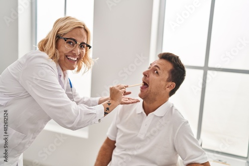 Middle age man and woman doctor and patient examining throat having medical consultation at clinic