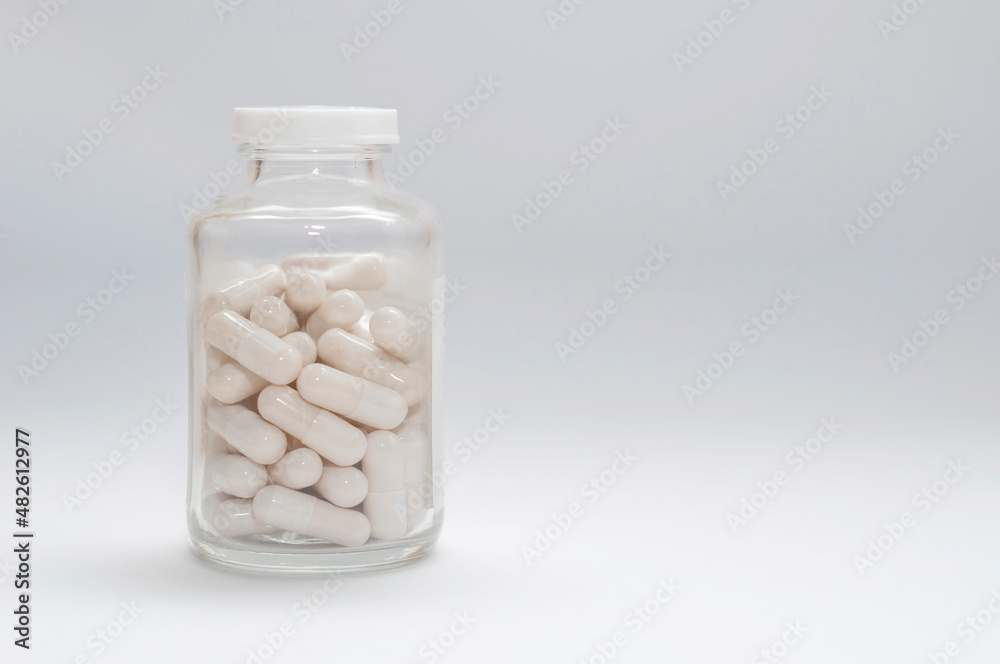 closed glass jar with pill capsules on a white background, copy space. closed glass jar with pill capsules on a white background, copy space.