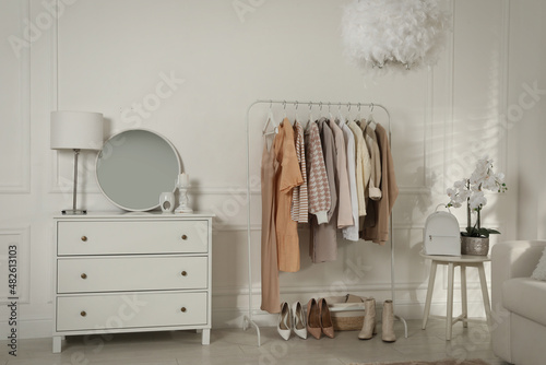 Modern dressing room interior with stylish clothes, shoes and beautiful orchid flowers © New Africa