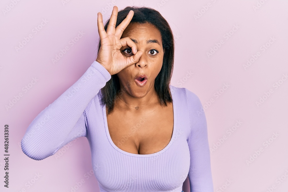 Young african american girl wearing casual clothes doing ok gesture shocked with surprised face, eye looking through fingers. unbelieving expression. Young african american girl wearing casual clothes doing ok gesture shocked with surprised face, eye looking through fingers. unbelieving expression.