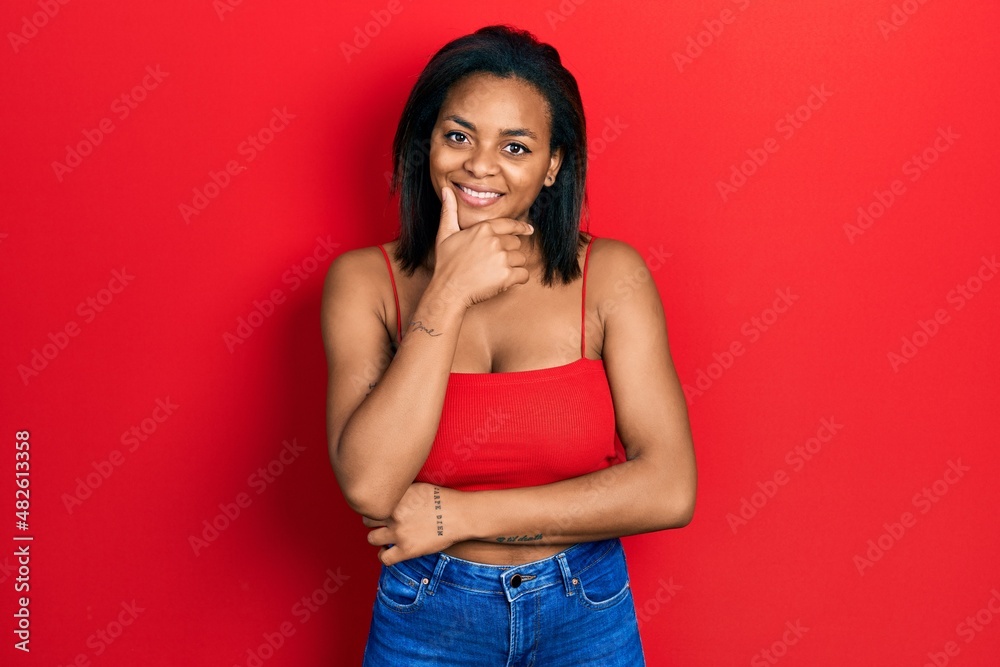Young african american girl wearing casual style with sleeveless shirt looking confident at the camera smiling with crossed arms and hand raised on chin. thinking positive. Young african american girl wearing casual style with sleeveless shirt looking confident at the camera smiling with crossed arms and hand raised on chin. thinking positive.