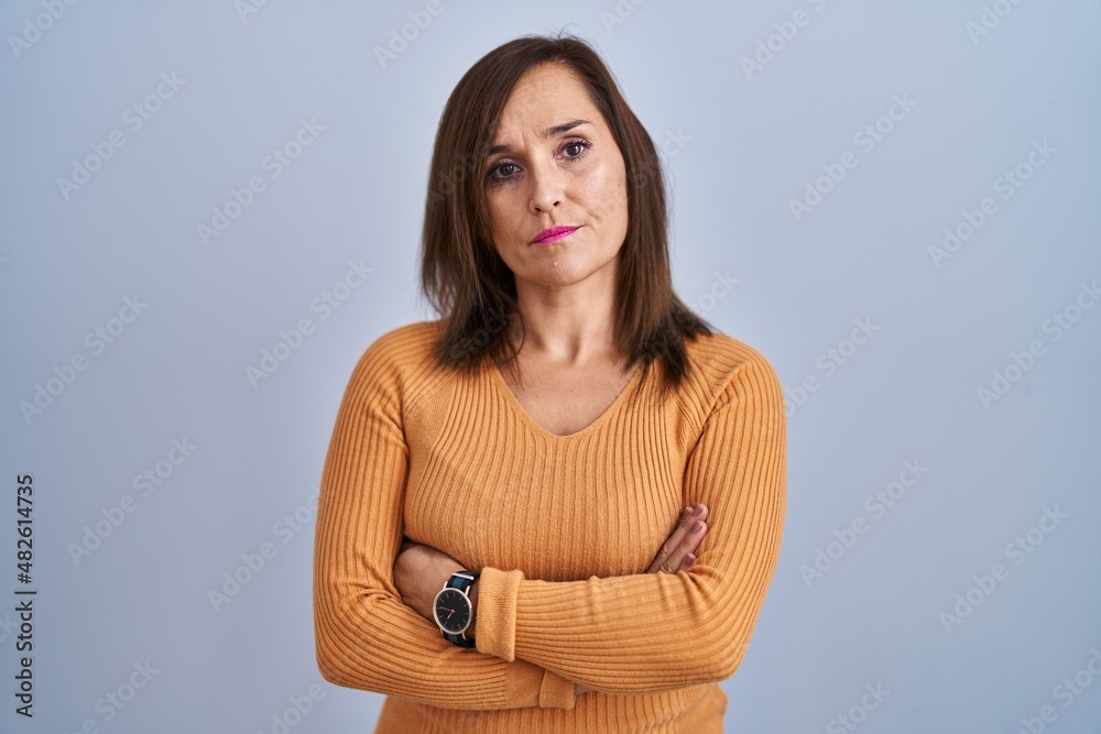 Obraz premium Middle age brunette woman standing wearing orange sweater skeptic and nervous, disapproving expression on face with crossed arms. negative person.
