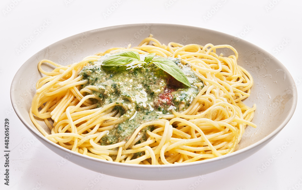 Plate of italian spaghetti pasta with pesto sauce over white isolated background Plate of italian spaghetti pasta with pesto sauce over white isolated background