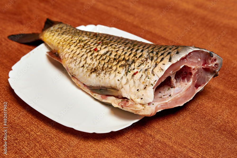 Peeled fish, seasoned with spices on a white plate. Peeled fish, seasoned with spices on a white plate.