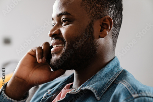 Black bristle man smiling while talking on cellphone