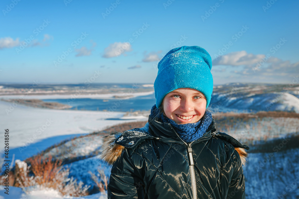 Portrait of a happy little girl on a mountain with a beautiful winter snowy landscape